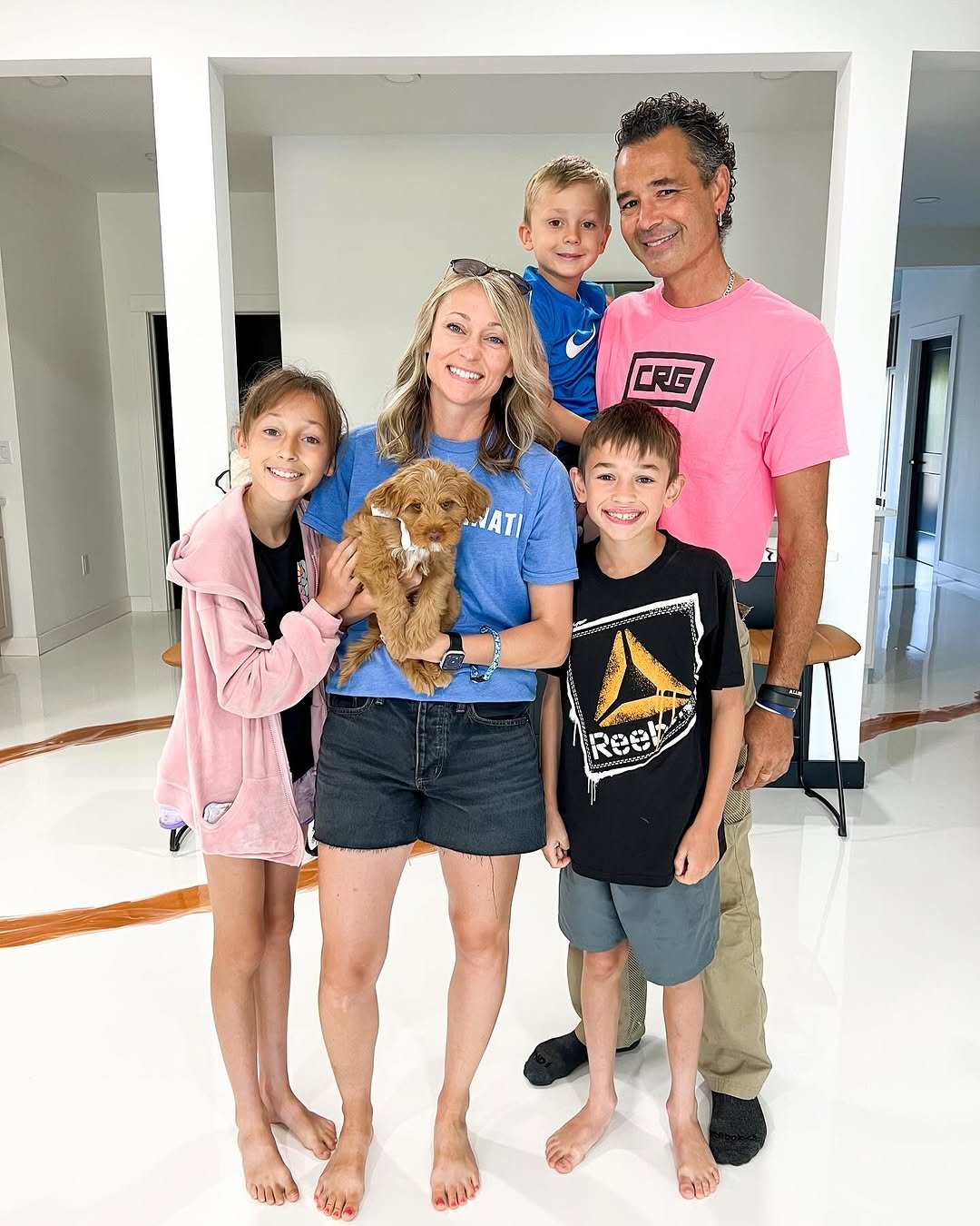 A smiling family holding a brown puppy together in a bright modern home interior